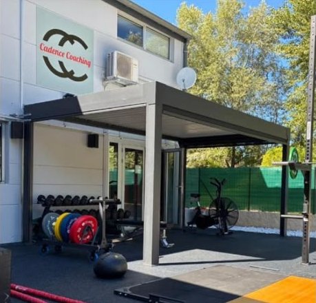 Park extérieur sous pergola avec disques de couleur, haltères et vélo à air